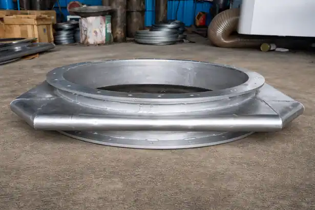 Side view of a circular metallic bellows expansion joint integrated with a square steel plate base