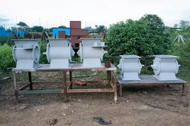 Five light gray industrial pocket feeders for bulk material handling arranged on an outdoor iron workbench frame