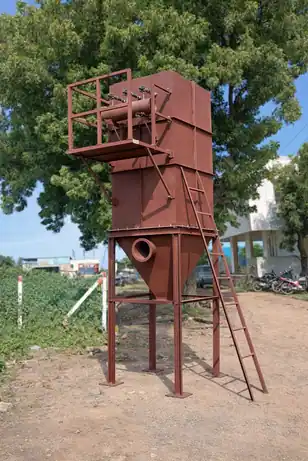 Reddish-brown vertical pulse-jet dust collector silo with hopper bottom and access ladder installed outdoors